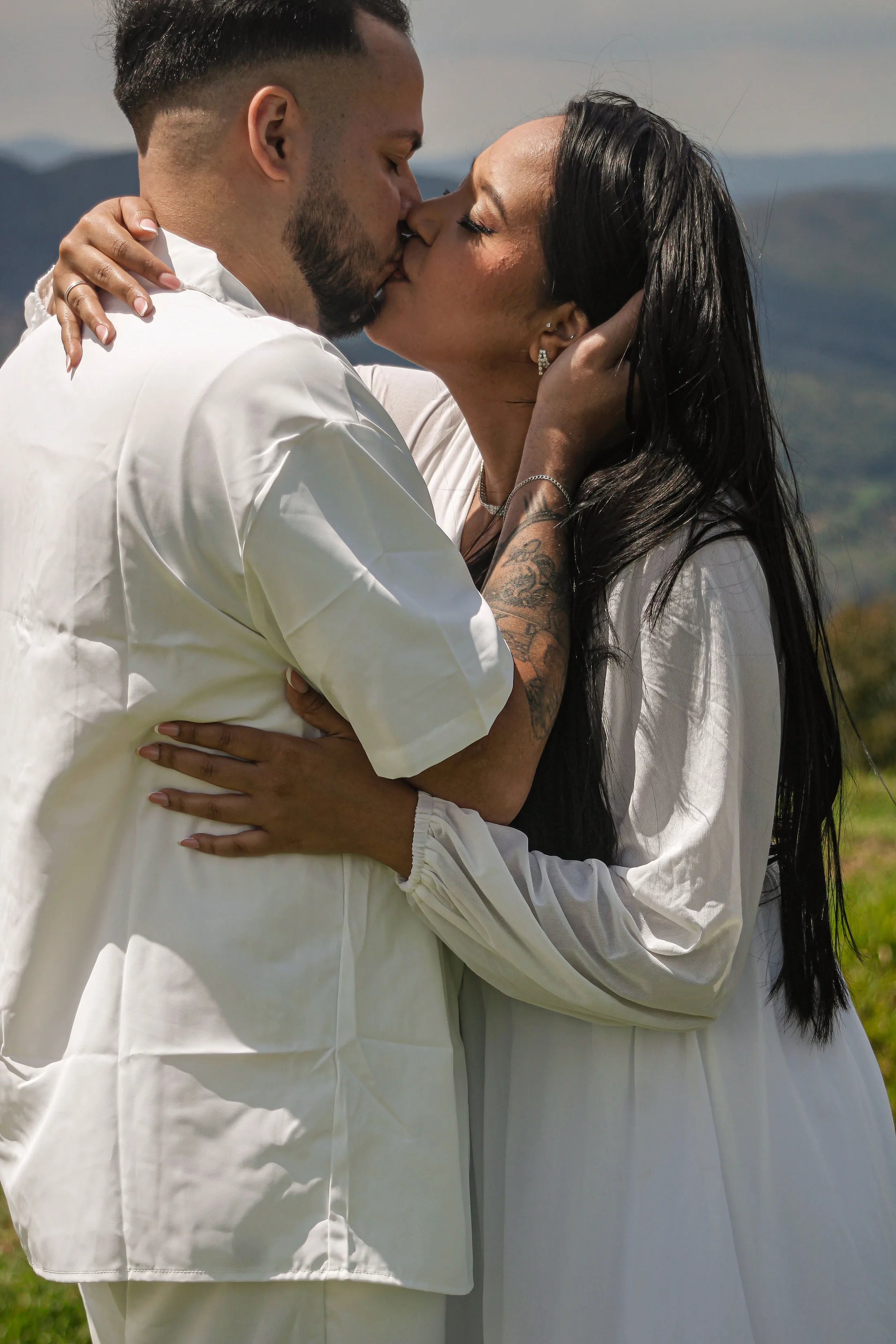 Casal de roupas brancas se beijando, em close.