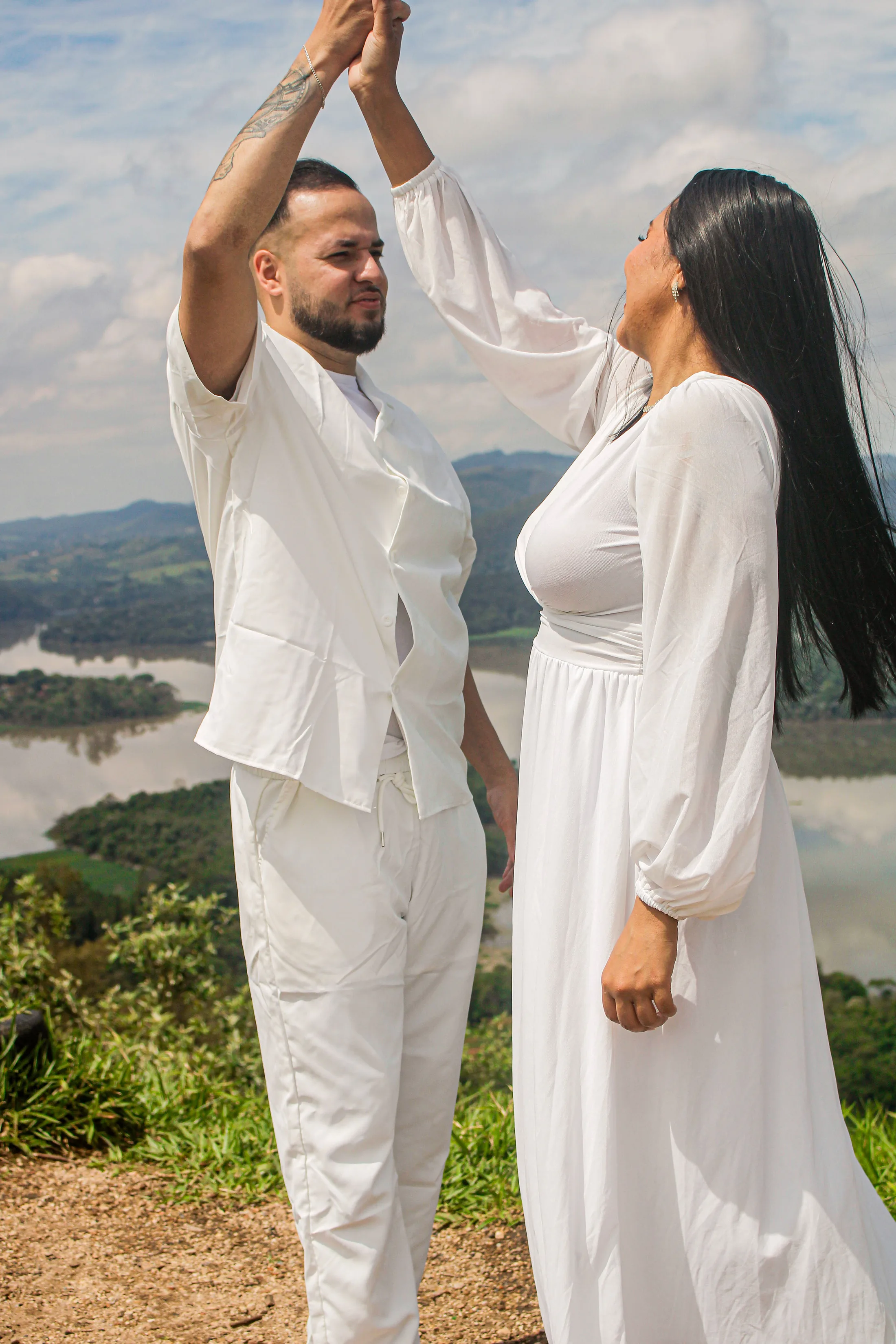 Casal dançando com uma das mãos erguidas, em um mirante.