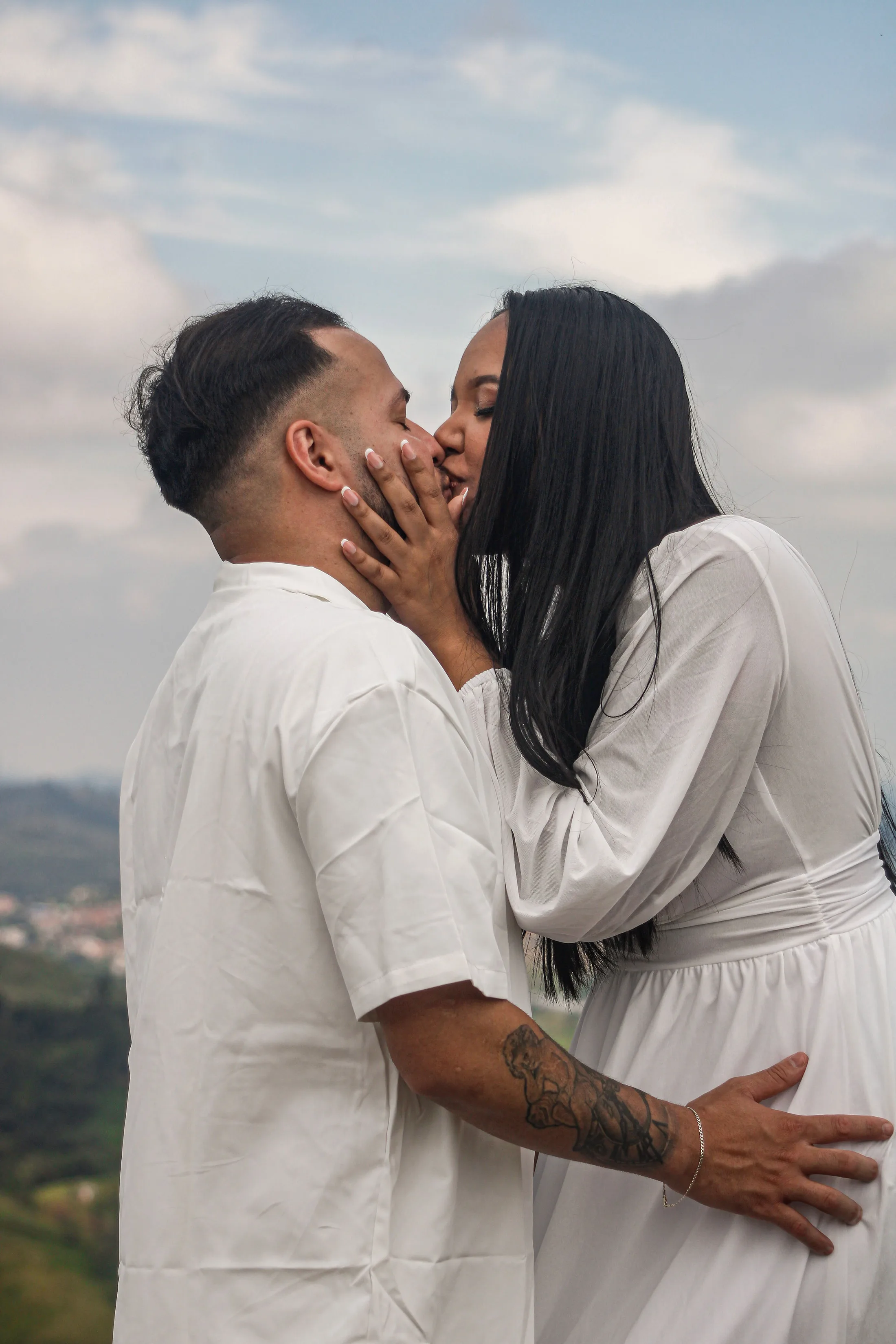 Casal se beijando, com céu ao fundo.